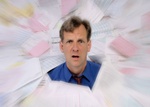 Mann schaut erschreckt gestresst aus Papierstapel