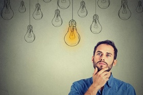 Portrait thinking handsome man looking up with idea light bulb above head isolated on gray wall back