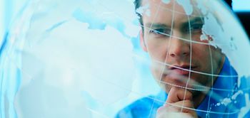 Mann schaut nachdenklich auf transparenten Globus