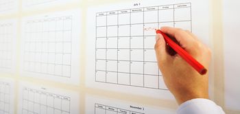 Mann schreibt Termin in Kalender an der Wand