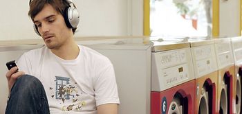 Mann sitzt im Waschsalon, hoert Musik