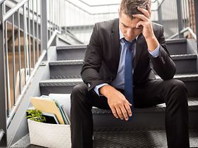 Mann sitzt nach Kündigung verzweifelt auf Treppe