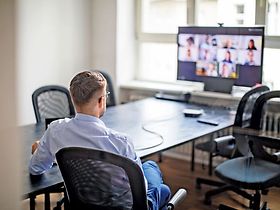 Mann sitzt vor virtuellem Teammeeting
