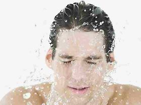Mann spritzt sich Wasser ins Gesicht