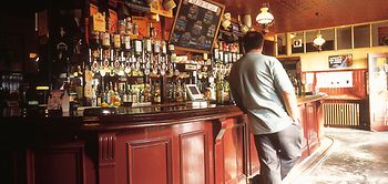 Mann steht allein an Kneipentheke