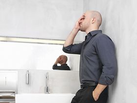 Mann steht erschoepft in Waschraum