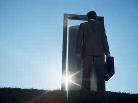 Mann steht mit Aktenkoffer vor einem Türrahmen