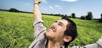 Mann steht mit ausgestreckten Armen in Getreidefeld, freut sich