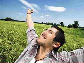 Mann steht mit ausgestreckten Armen in Getreidefeld, freut sich