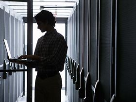 Mann steht mit Laptop in Datencenter