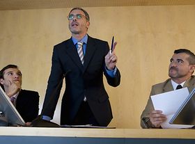 Mann steht zwischen zwei Sitzenden