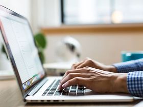Mann tippt im Homeoffice in den Laptop