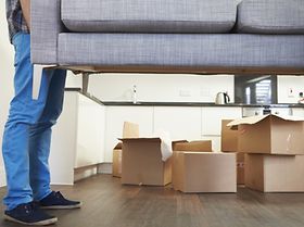 Mann trägt Couch in Wohnung