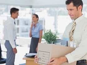 Mann trägt nach Kündigung seine Arbeitsmaterialien aus Büro