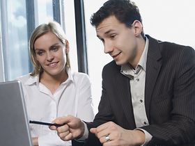 Mann und Frau sitzen im Büro an Laptop
