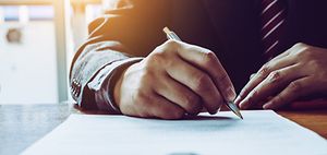 Mann unterschreibt Dokument (1)