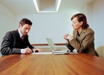 Businessman and woman in meeting, laptop on table
