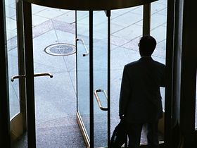 Mann verlässt Bürogebäude durch Drehtür