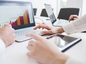 mehrere Hände arbeiten an Statistik auf Laptop