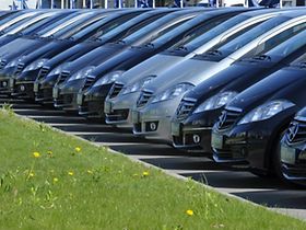 Mehrere Pkw in einer Reihe mit Gras im Vordergrund