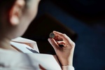 Businesswoman looking at one euro coin in sunlight.