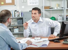 Mitarbeiter diskutieren an Schreibtisch über Pläne