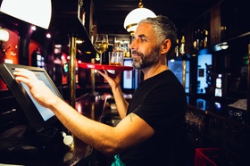 26 Oct 2014, Vienna, Austria --- Waiter holding tray with beverages in an Irish pub while operating