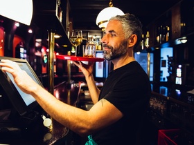 26 Oct 2014, Vienna, Austria --- Waiter holding tray with beverages in an Irish pub while operating
