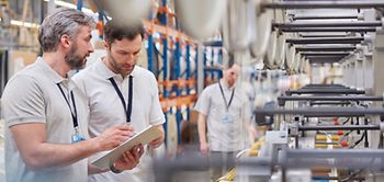 Mitarbeiter mit Klemmbrett an Maschine