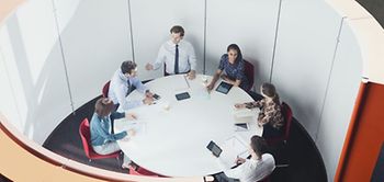 Mitarbeiter sitzen in abgeschirmter Büromuschel