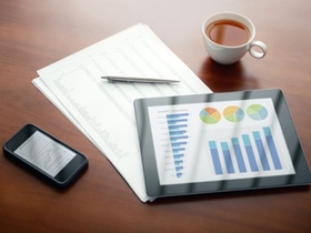 Modern workplace with digital tablet and mobile phone, pen and papers with numbers.