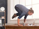Short break for yoga in office. Flexible man practicing yoga at workplace, making balance exercise o