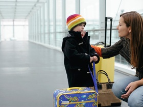 Mutter und Sohn stehen mit Koffern in einem Uebergang am Flughafen