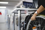 Woman with face mask sitting in wheelchair working in modern office