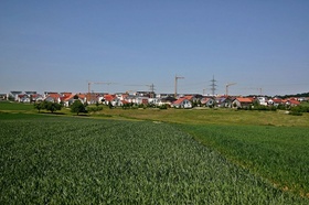 Neubaugebiet_grüne Wiese Neubauten Kräne im Hintergrund