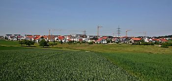 Neubaugebiet_grüne Wiese Neubauten Kräne im Hintergrund