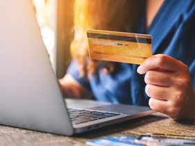 Nahaufnahme einer Geschäftsfrau, die eine Kreditkarte hält und einen Laptop benutzt