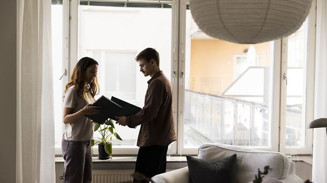 Paar hält Ordner neben dem Fenster