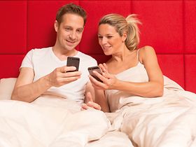 Paar im Bett mit Smartphones