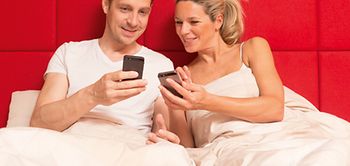 Paar im Bett mit Smartphones