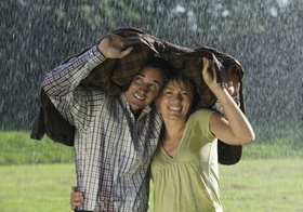 Paar steht unter Jacke im Regen