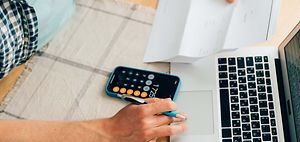 Person berechnet Kosten und Steuern am Laptop