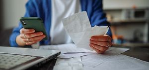 Person sortiert Belege und Rechnungen am Küchentisch