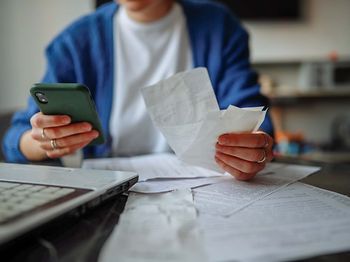 Person sortiert Belege und Rechnungen am Küchentisch