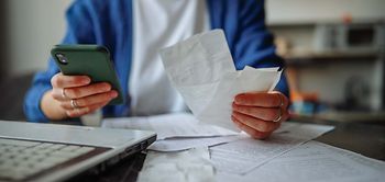 Person sortiert Belege und Rechnungen am Küchentisch