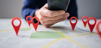 Person Using Map With Red Location Markers On Mobile Phone