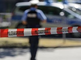 Polizeiabsperrung mit Flatterband, Streifenwagen und Polizist