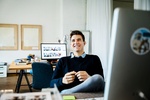 Portrait of young casual businessman sitting on his desk