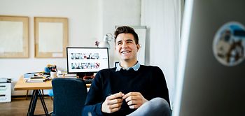 Portrait of young casual businessman sitting on his desk