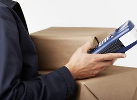 Postbote schaut auf Scanner und Paket